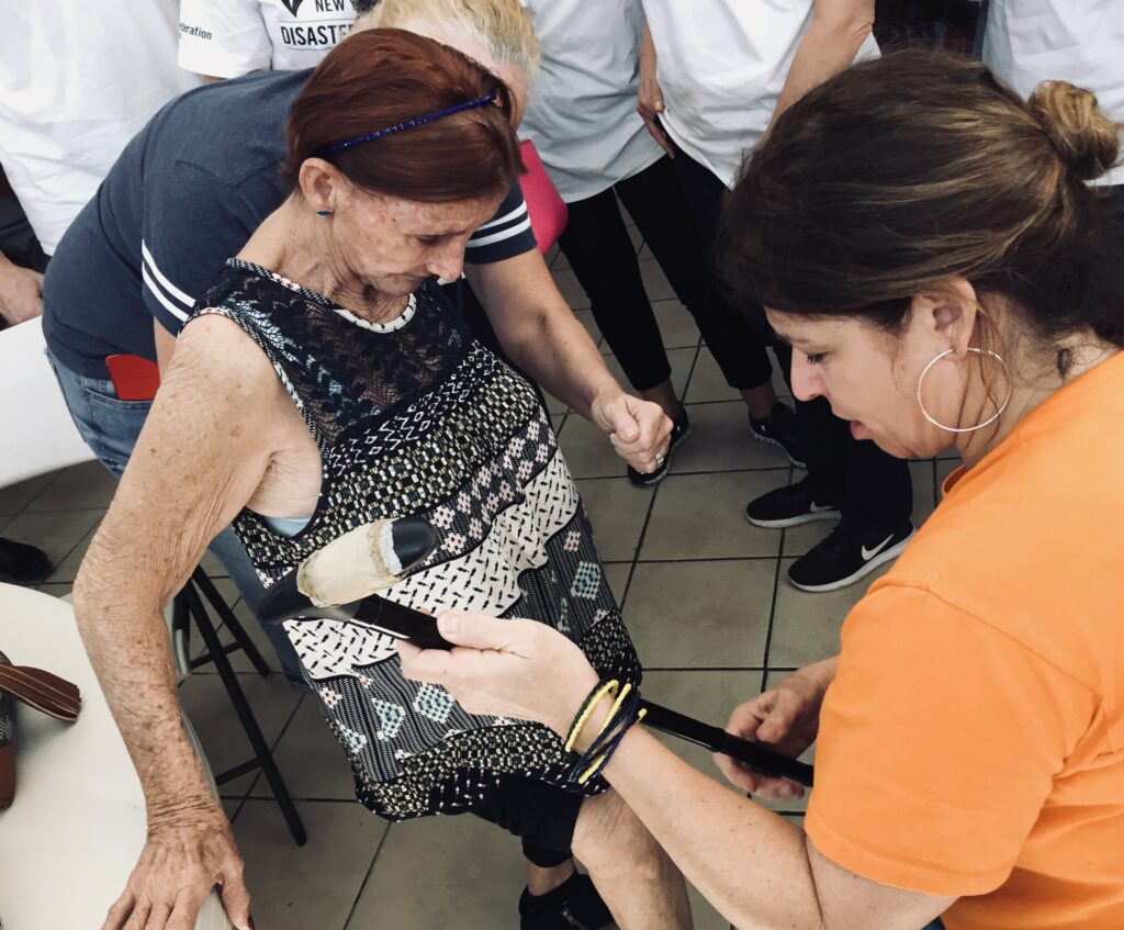An older woman is being handed a can as she looks at Afya founder Danielle Butin.